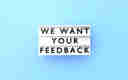 'We want your feedback' sign on a blue background